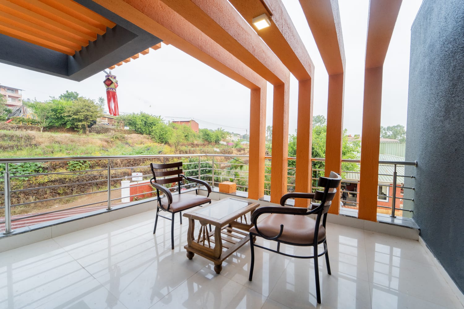 The Tranquil Terrace room balcony with orange wooden fins, two chairs and a table overlooking the trees